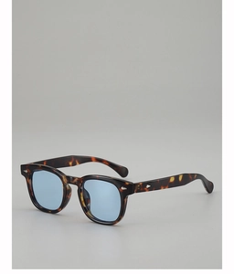 Close-up of tortoise shell sunglasses with blue tinted lenses and silver arrow detail
