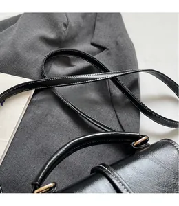 Detail of matte black leather bag with contrast stitching and golden hardware
