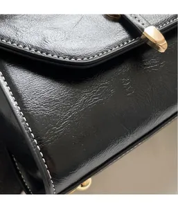 Detailed close-up of black PU leather bag with contrast white stitching and gold hardware