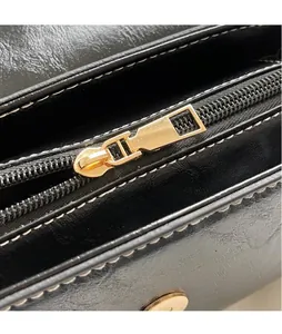 Detailed shot of golden zipper hardware and white contrast stitching on black leather bag