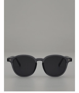Close-up of translucent grey oval sunglasses featuring silver metal rivet decorations