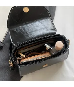 Detailed interior of black matte leather bag showing spacious compartments and white stitching
