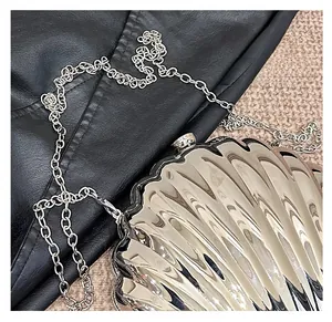 Dettaglio della pochette a conchiglia argento lucido con strisce radiali e catenina