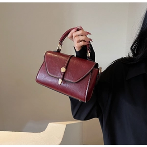 Detailed close-up of retro burgundy faux leather square bag with white stitching detail
