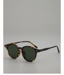 Detail view of tortoiseshell oval sunglasses with dark green lenses and silver hinge accents