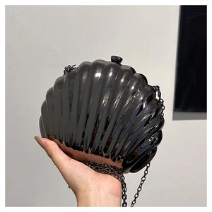 Dettaglio di una pochette da sera nera a forma di conchiglia con finitura metallica e catena