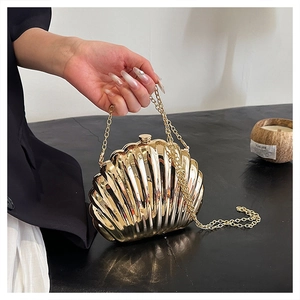 Dettaglio di una borsa a mano dorata a forma di conchiglia con trama e catena sottile