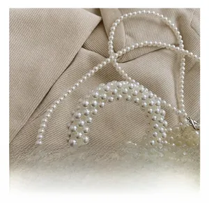 Detail of beaded pearl handbag showing round handle and silver metal lobster clasp closure