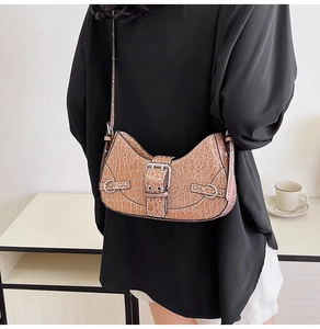 Détail d'un sac demi-lune marron motif crocodile avec boucles argentées sur un mannequin