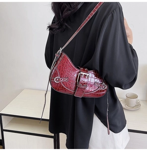 Model wearing a retro burgundy crocodile pattern saddle bag with a silver metal buckle