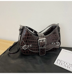 Detail of dark brown crocodile texture hobo bag with silver metal buckles and rivets