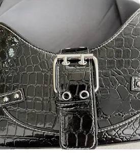 Détail du cuir noir brillant gaufré crocodile avec boucle en métal argenté et rivets