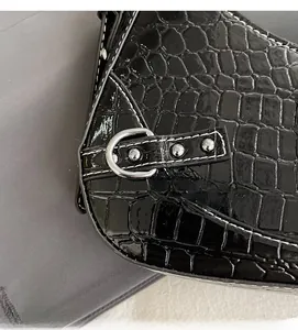 Détail de la texture en cuir noir gaufré crocodile avec boucle en D en métal argenté