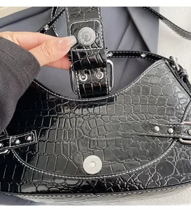 Détail du sac en cuir crocodile noir avec boucle magnétique et coutures contrastées