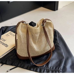 Detail of woven straw shoulder bag with dark brown leather base on a black leather jacket