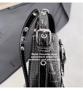 Détail des œillets métalliques et coutures blanches sur la bandoulière en similicuir noir