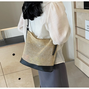 Detail of woven straw shoulder bag with black leather trim and hollow-out texture design