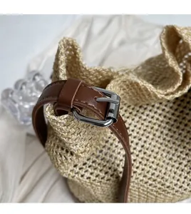 Detail of woven straw bag texture with brown leather adjustable shoulder strap and buckle