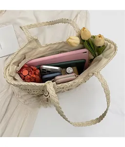 Vue intérieure d'un grand sac cabas tressé beige contenant tablette et accessoires variés