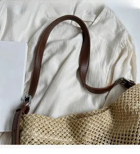 Detail of woven straw bag with adjustable brown leather handle and silver metal buckle
