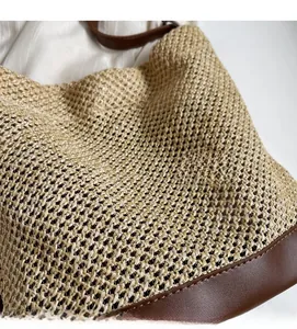 Detail of woven straw bag with premium brown faux leather straps and base stitching