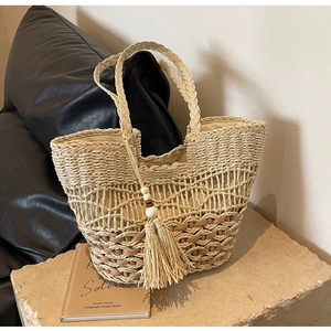 Détail du motif tressé ajouré d'un sac cabas avec pompon à franges et perles en bois