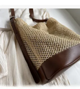 Detail of the woven straw texture and premium dark brown leather strap on a shoulder bag