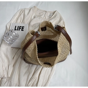 Detail of beige hollow woven bag featuring adjustable brown leather strap and inner pouch