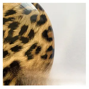 Macro shot of glossy leopard print fabric texture on a stylish crossbody chain bag