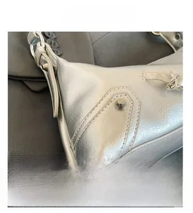 Close-up of metallic silver leather texture with rivets and precise stitching details