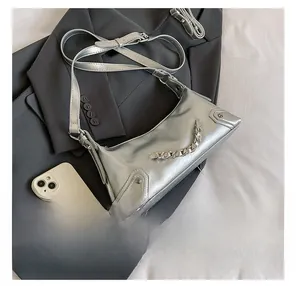 Detail view of silver crossbody bag with metallic chain compared to a smartphone