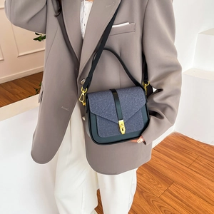 Two-tone blue denim and black leather saddle bag with gold buckle on a model