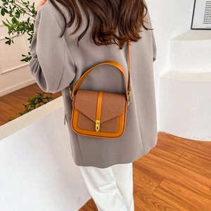 Vintage brown leather saddle bag with gold metal buckle shown on a model's shoulder