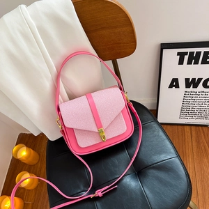 Pink patchwork saddle bag with woven texture and gold buckle on a stylish chair