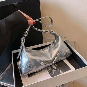 Detail of silver Y2K hobo bag with metallic chains and rivets on an adjustable strap
