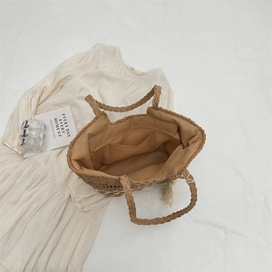 Sac à main tressé marron avec pompons et doublure intérieure sur tissu blanc élégant