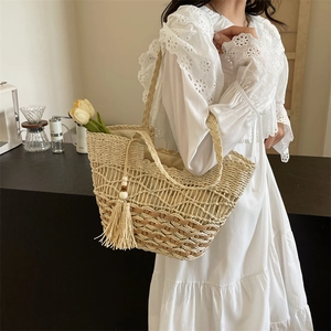Sac fourre-tout tressé beige et marron clair avec franges porté par un mannequin chic