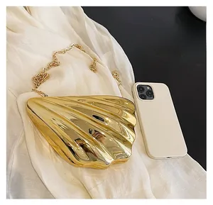 Detailansicht der goldenen Muschel-Abendtasche mit Metallic-Textur und Kettenriemen