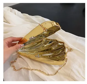 Makroansicht der goldenen Abendtasche in Muschelform mit Metallic-Textur und Kette