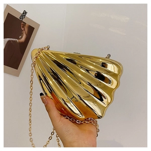 Detail einer goldenen Abendtasche in Muschelform mit Perlenverschluss und Kettenriemen