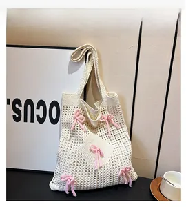 Detail of cream crochet woven bag featuring decorative pink bows and open knit mesh design
