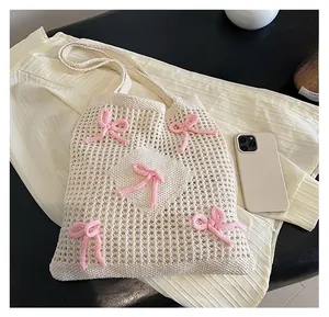 Detailed view of cream knit tote bag with pink 3D bows and mesh bottom texture