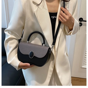 Detail of two-tone crossbody bag featuring grey textured flap and elegant metal buckle