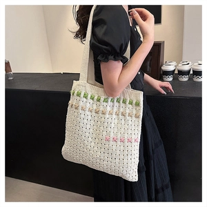 Detail of cream woven tote bag with colorful embroidery stripes on a female model