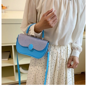 Detail of sky blue handbag featuring silver woven flap and elegant top handle on model