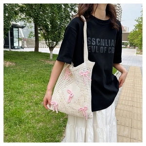 Outdoor shot of a white crochet shoulder bag with pink bows and mesh weave design