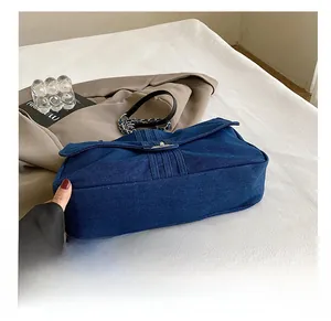 Detail of durable denim tote bottom with precise stitching and metallic chain accents