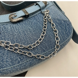 Nahaufnahme der Vintage-Denim-Textur mit silbernen Ketten und Metallschnalle