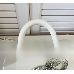 Detail of white leather handbag featuring a sparkling rhinestone bow and a curved top handle