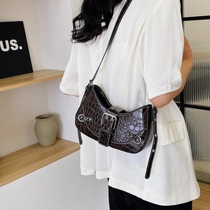 Deep brown crocodile texture moon bag with silver buckle worn on model's shoulder
